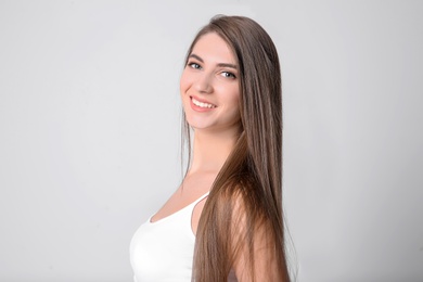 Portrait of young woman with long beautiful hair on light background