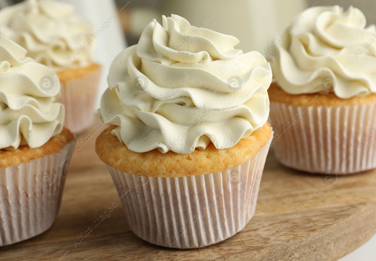 Photo of Tasty vanilla cupcakes with cream on table, closeup