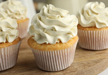 Tasty vanilla cupcakes with cream on table, closeup