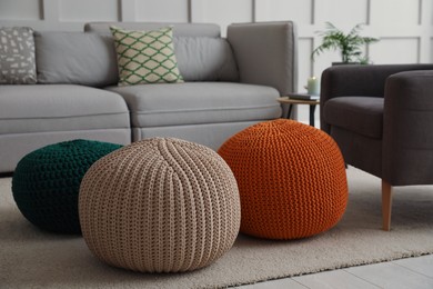 Photo of Living room interior with different stylish knitted poufs and sofa