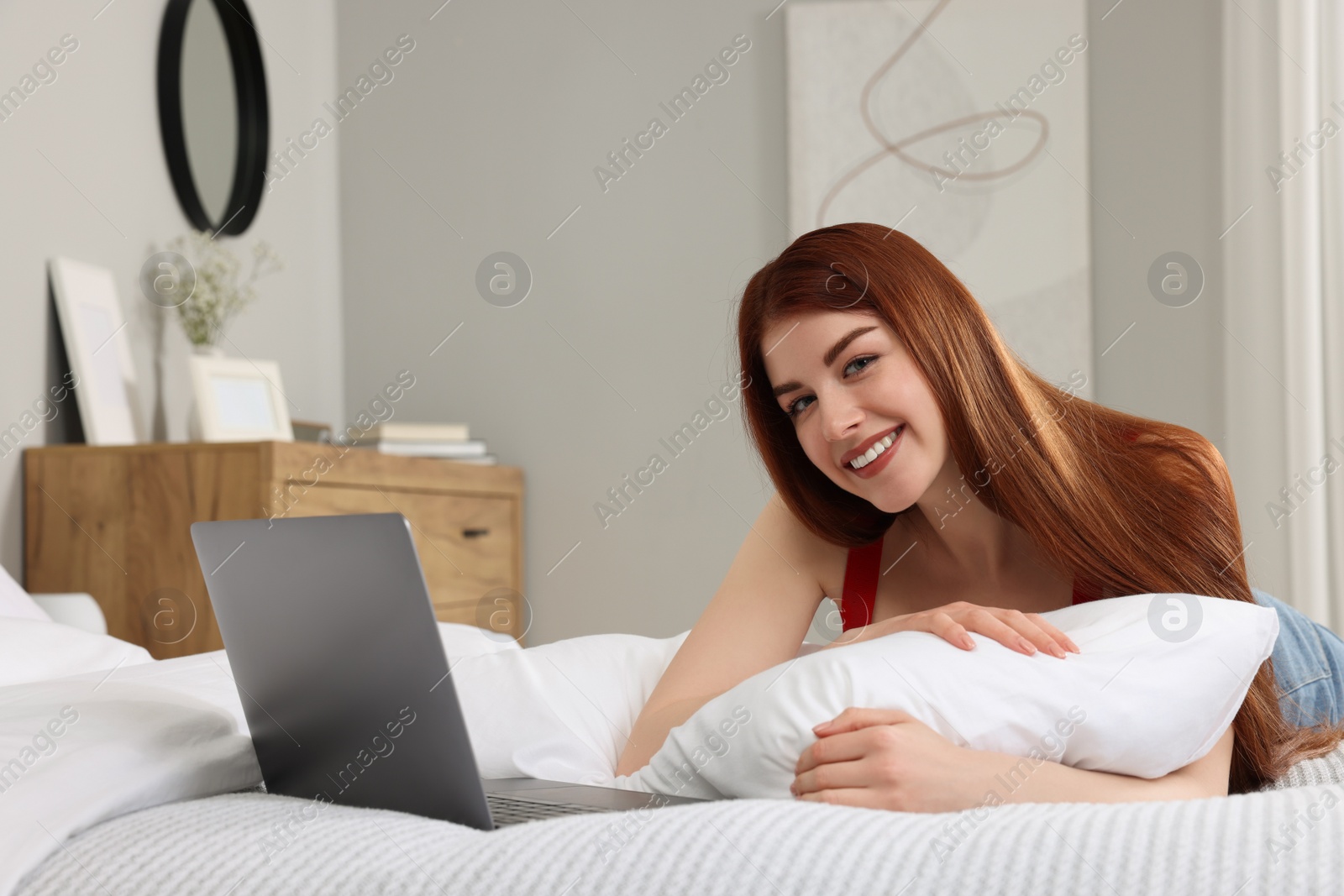 Photo of Happy woman with laptop on bed in bedroom