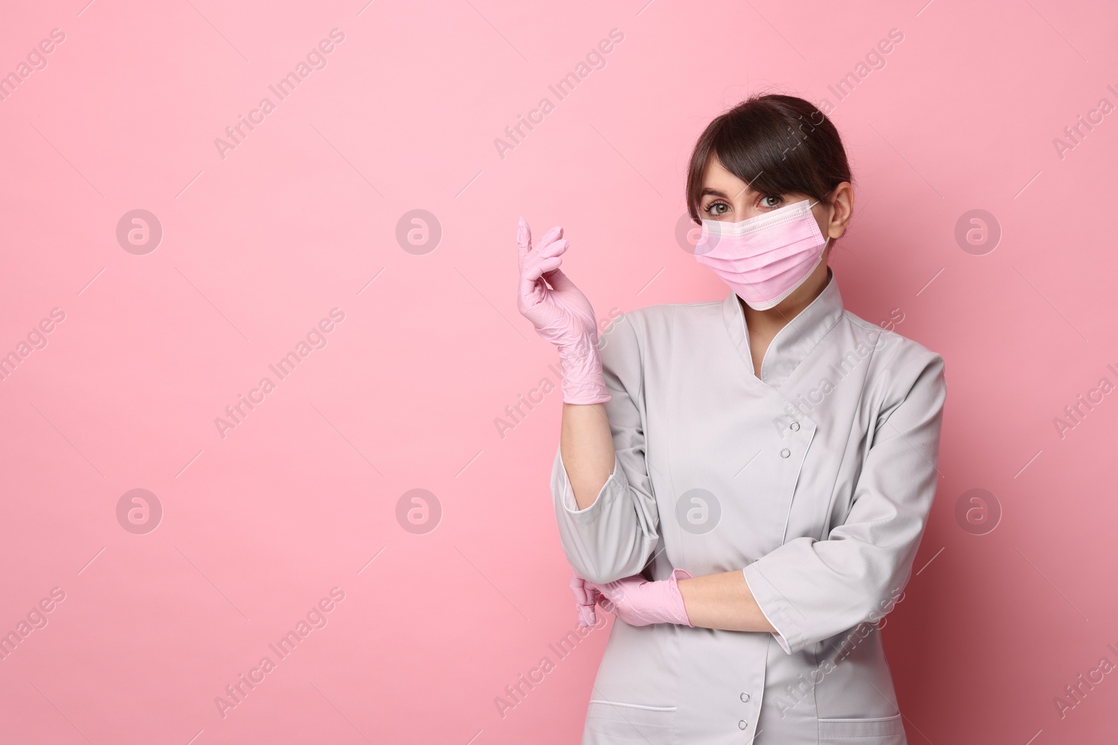 Photo of Cosmetologist in medical uniform on pink background, space for text