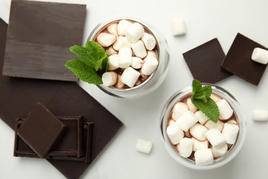 Photo of Glasses of delicious hot chocolate with marshmallows and fresh mint on white table, flat lay