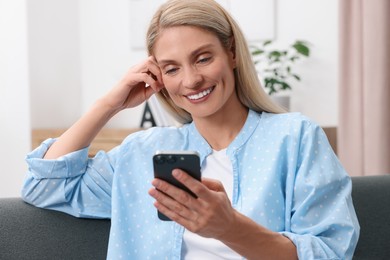 Photo of Woman sending message via smartphone at home