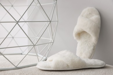 Photo of Soft fluffy white slippers near grey wall