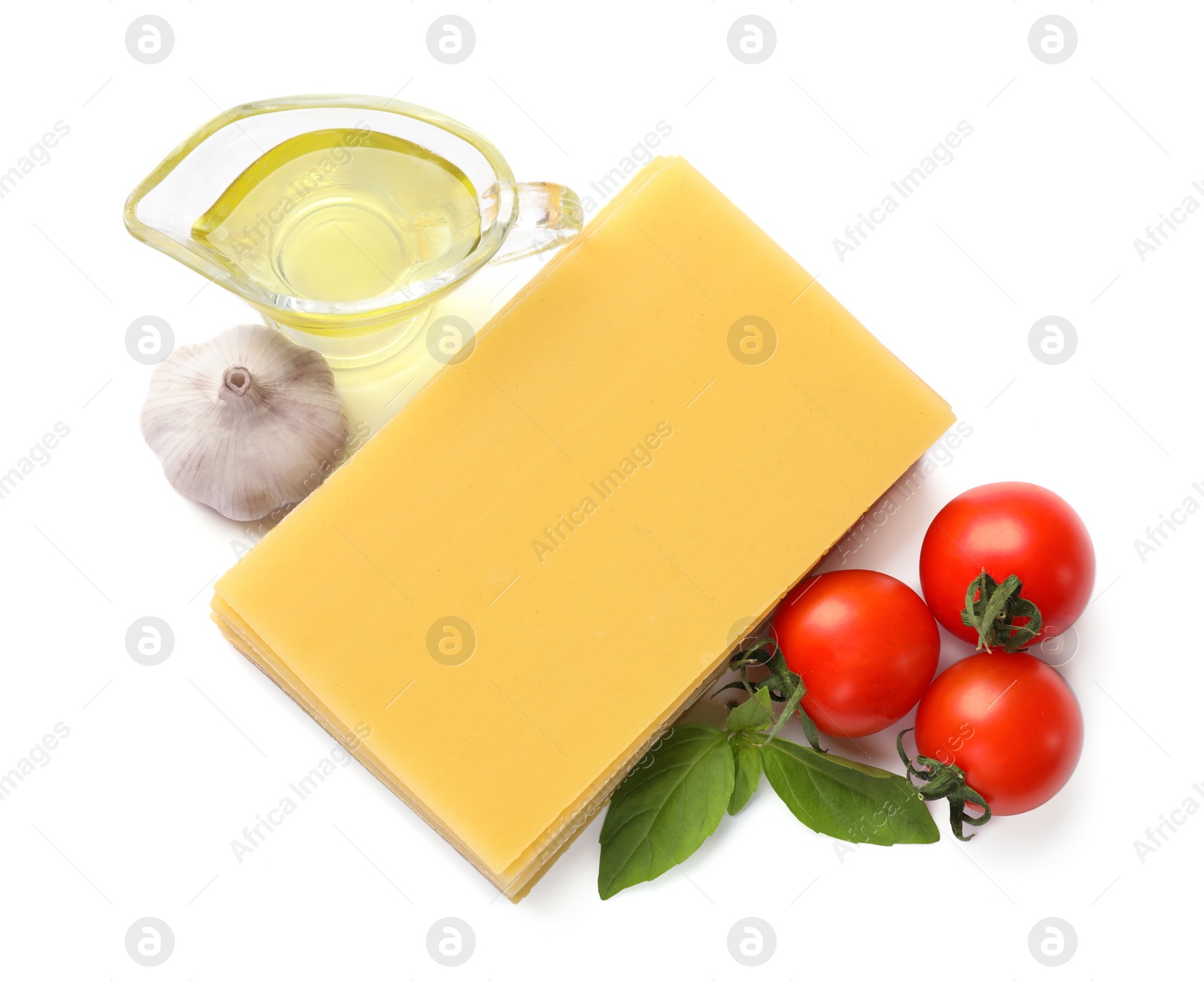 Photo of Stack of uncooked lasagna sheets, tomatoes, oil and garlic isolated on white, top view