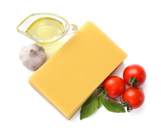 Stack of uncooked lasagna sheets, tomatoes, oil and garlic isolated on white, top view