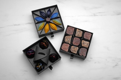Boxes of tasty chocolate candies on white marble table, flat lay