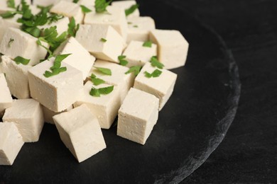 Photo of Delicious tofu with parsley on black table, closeup