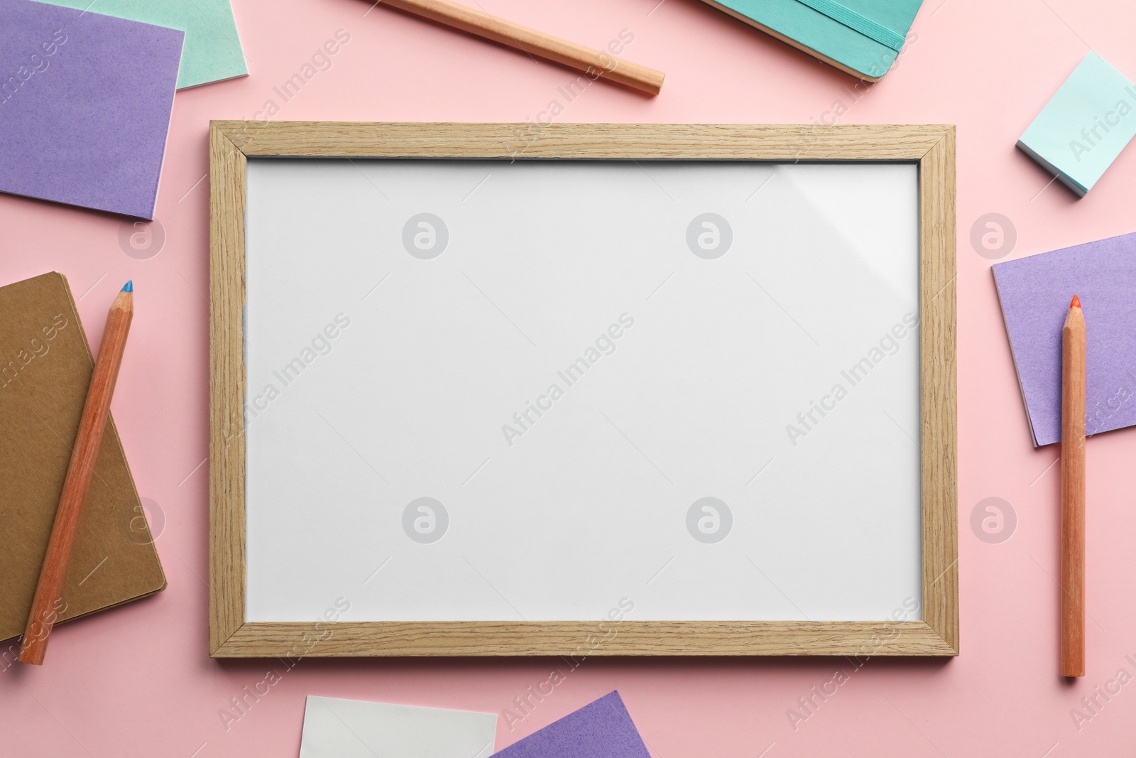 Photo of Blank white board with stationery on light pink background, flat lay. Space for text