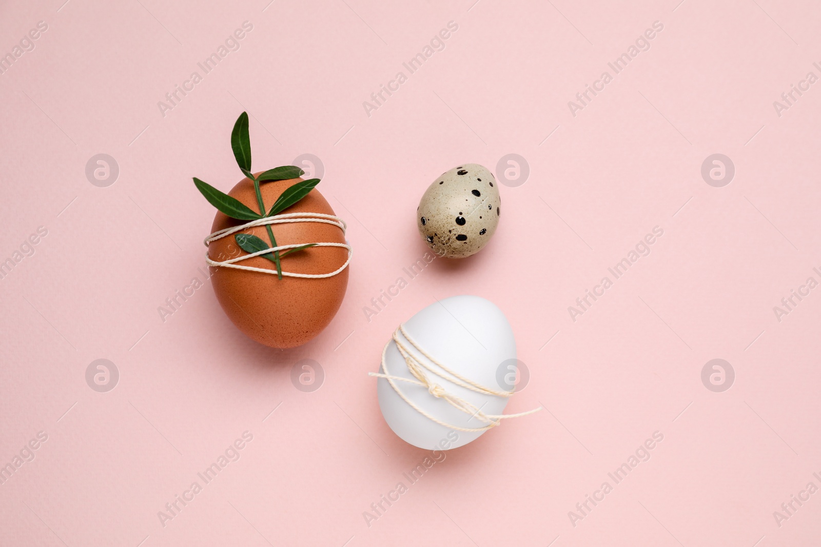 Photo of Beautifully decorated Easter eggs on pale pink background, flat lay