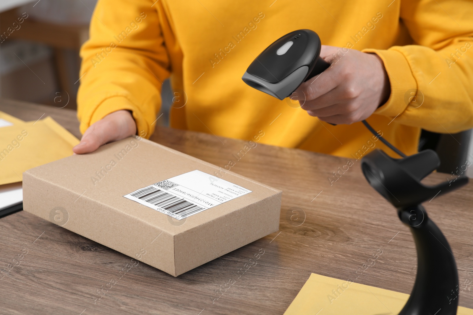 Photo of Seller with scanner reading parcel barcode at workplace, closeup. Online store