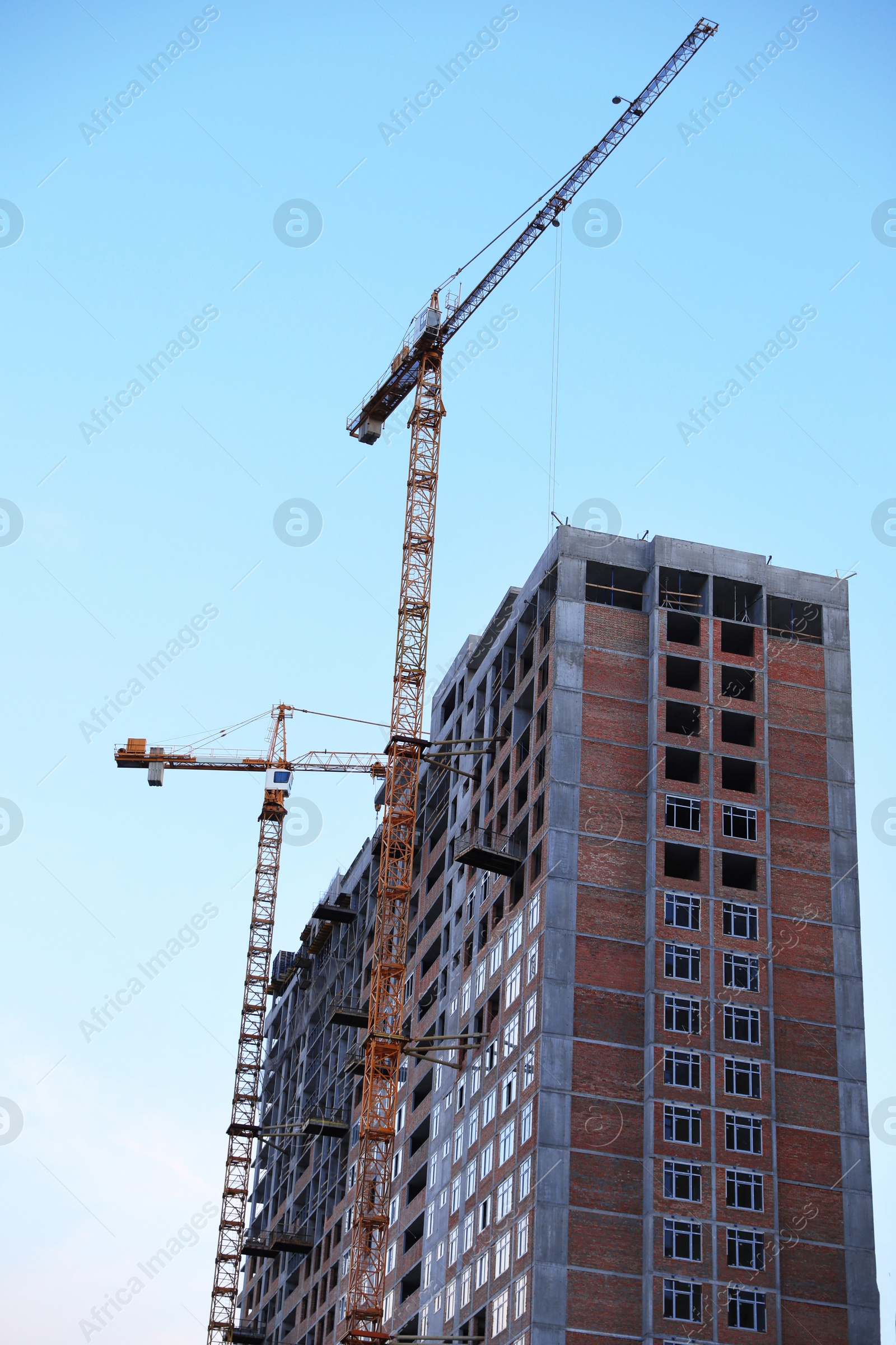 Photo of Construction crane and unfinished building against blue sky