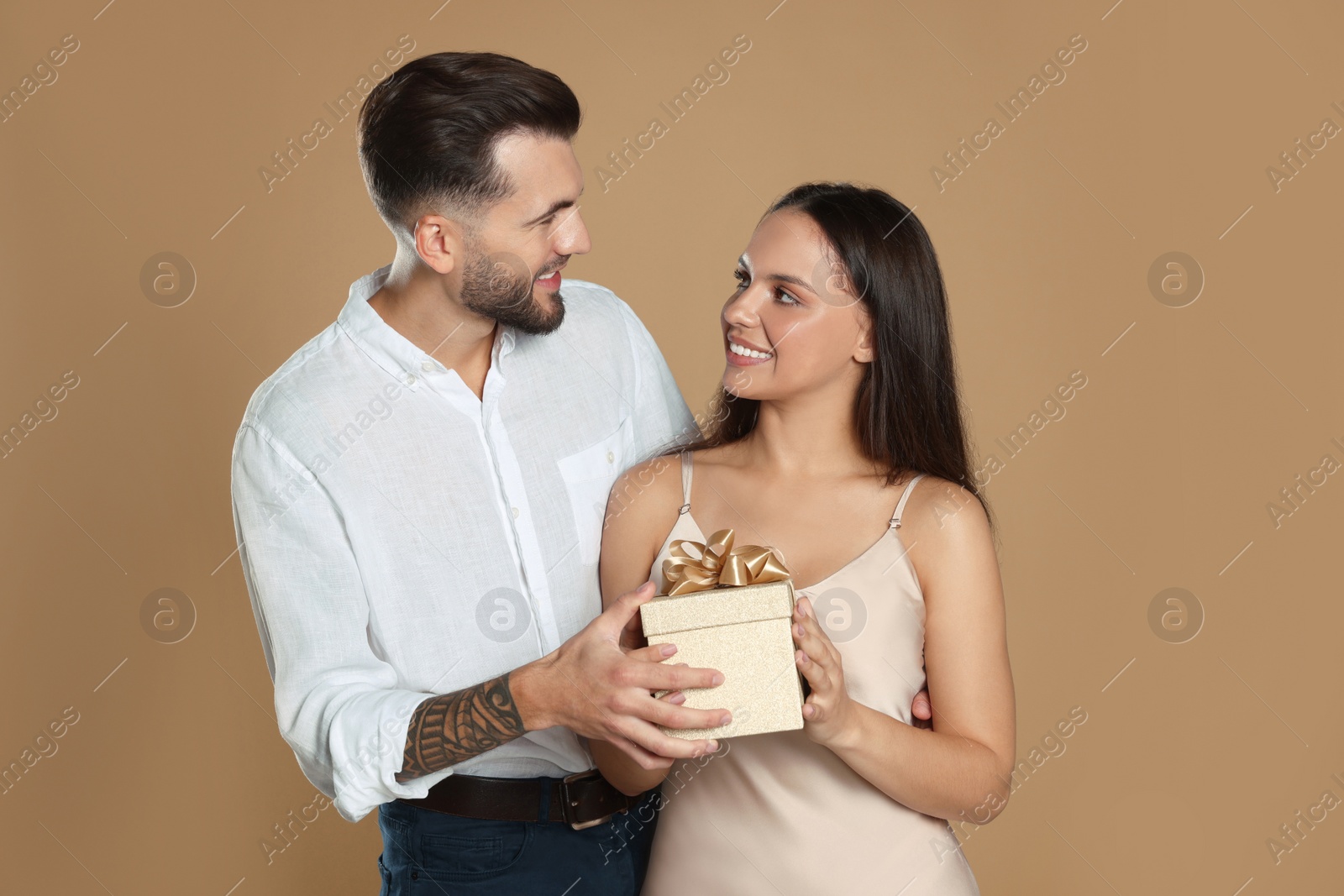 Photo of Lovely couple with gift on beige background