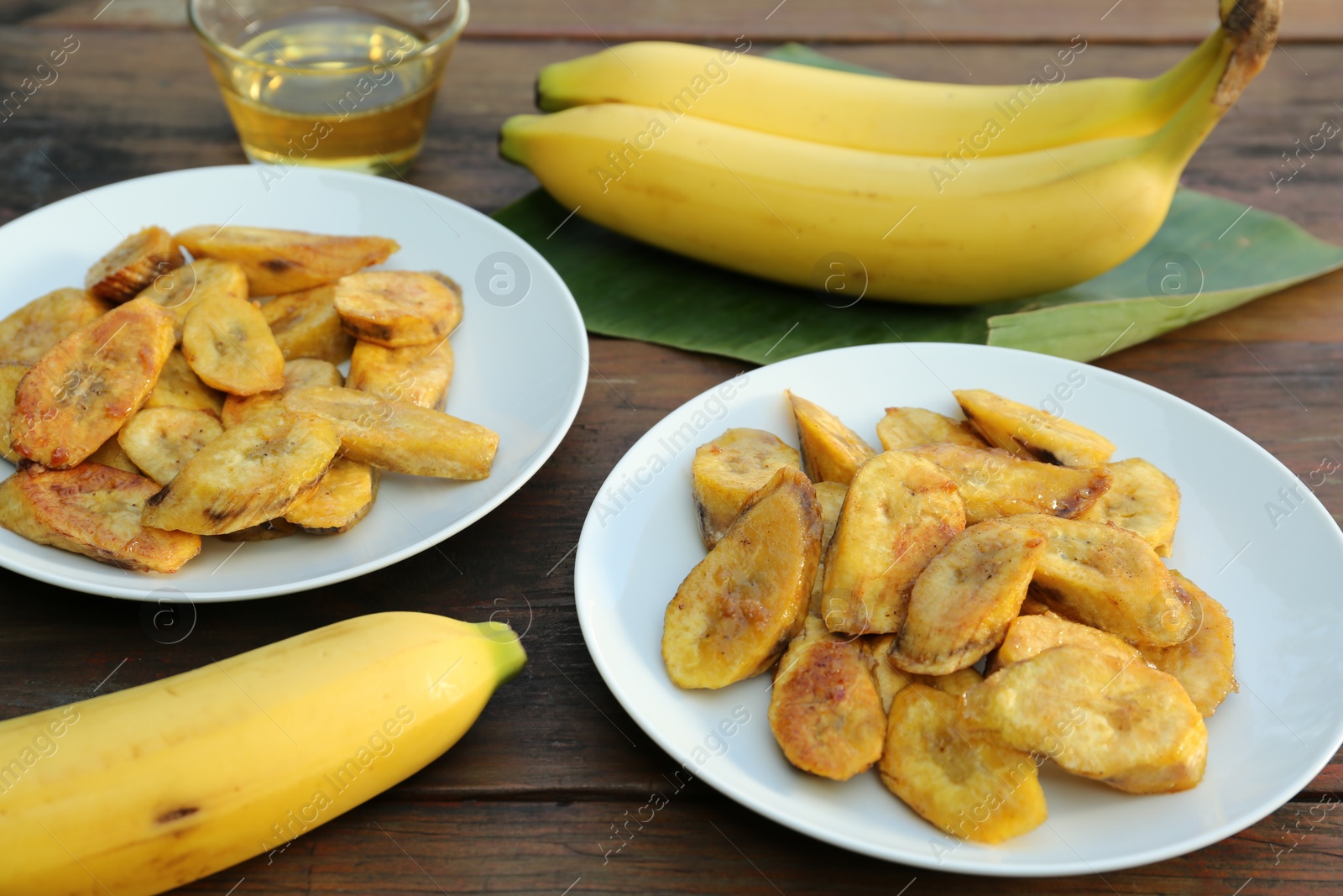 Photo of Tasty deep fried banana slices and fresh fruits on wooden table