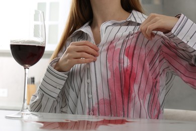 Woman with spilled wine over her shirt and marble table in kitchen, closeup