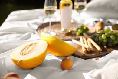 Photo of Delicious melon and peach on picnic blanket, closeup