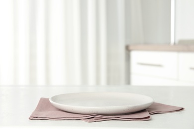 Photo of Empty plate and napkin on white table indoors. Space for text