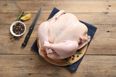 Fresh raw chicken with spices and knife on wooden table, flat lay