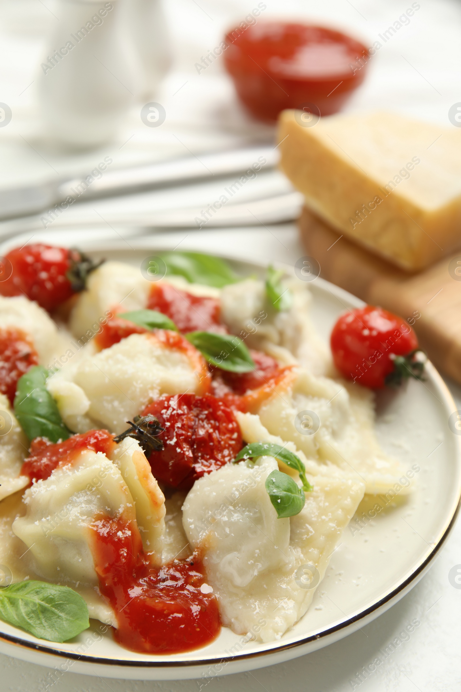 Photo of Tasty ravioli with tomato sauce served on white table, closeup