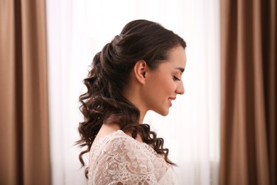 Photo of Happy young bride with beautiful wedding hairstyle indoors