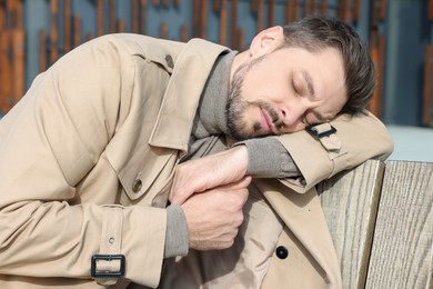 Photo of Tired man sleeping on bench outdoors, closeup