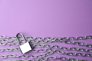 Steel padlock, chains and space for text on purple background, flat lay. Safety concept
