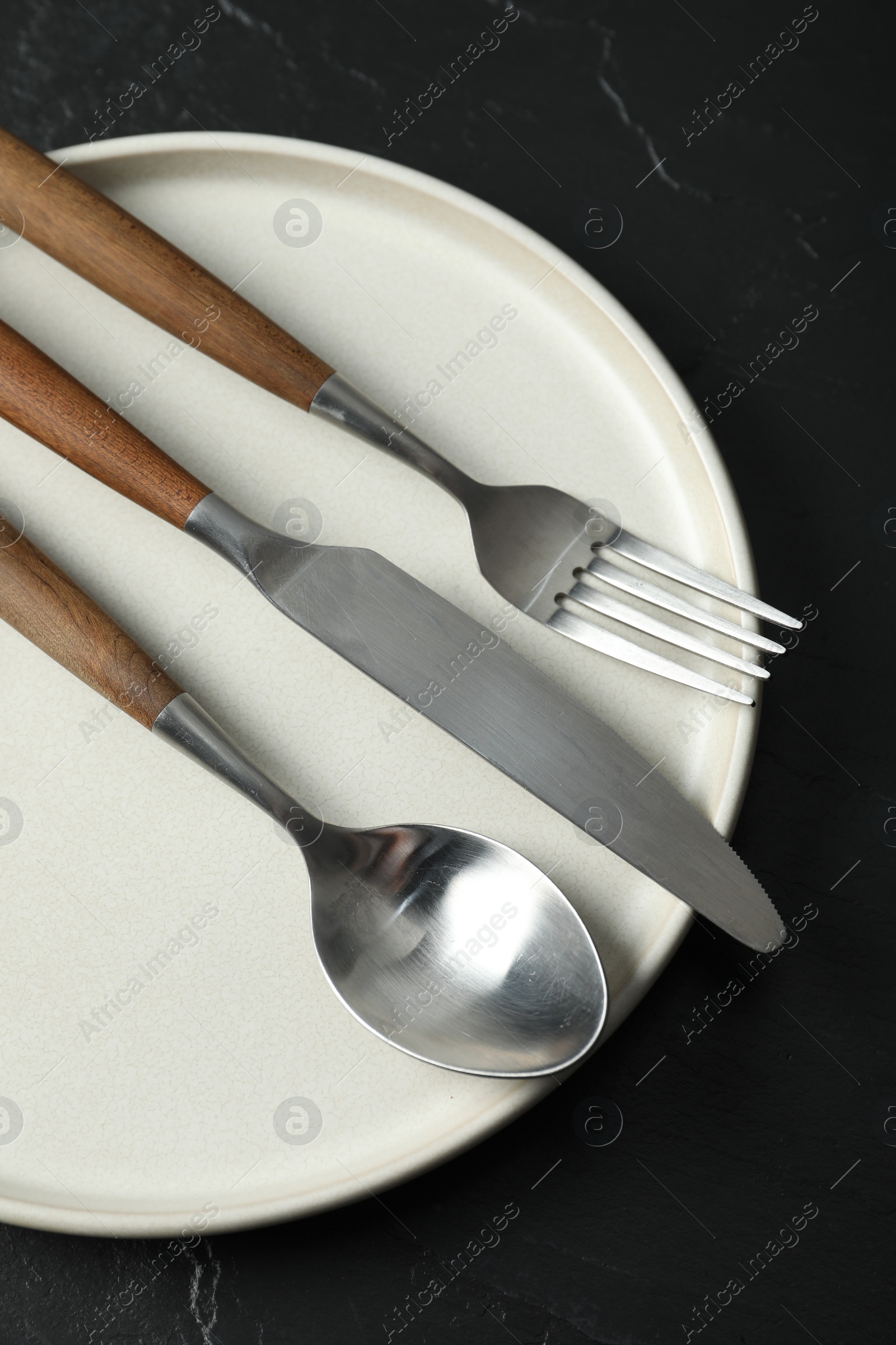 Photo of Stylish cutlery and plate on black table, top view