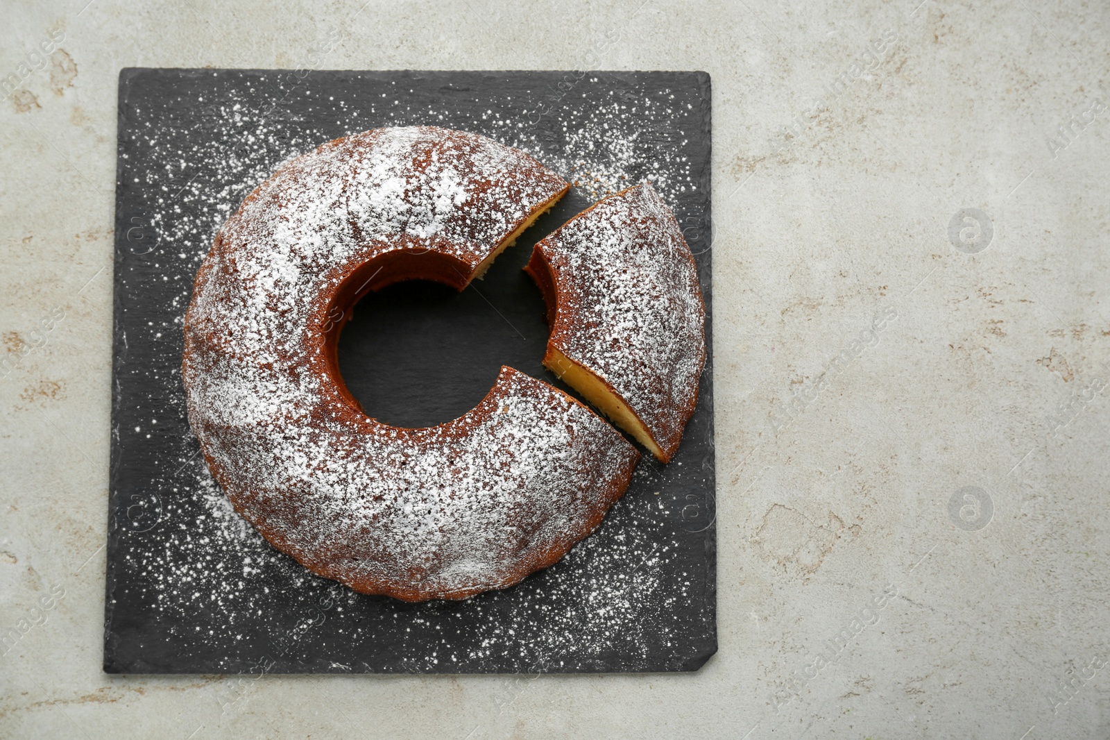 Photo of Homemade yogurt cake with powdered sugar on light grey table, top view. Space for text