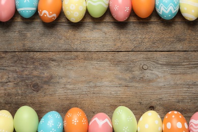 Flat lay composition of painted Easter eggs on wooden background, space for text