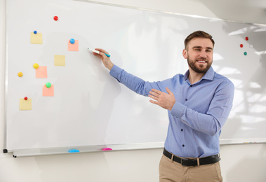 Portrait of young teacher writing on whiteboard in classroom