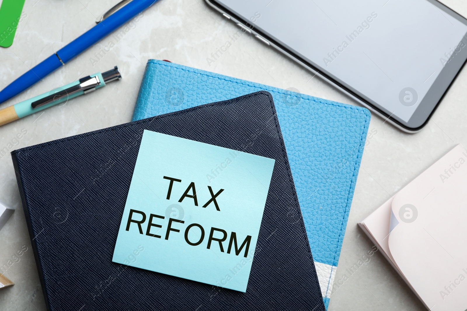 Image of Reminder note with words TAX REFORM and stationery on table, flat lay