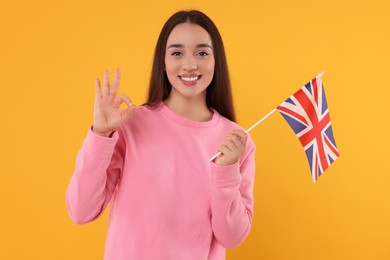 Photo of Young with flag of United Kingdom showing ok gesture on orange background