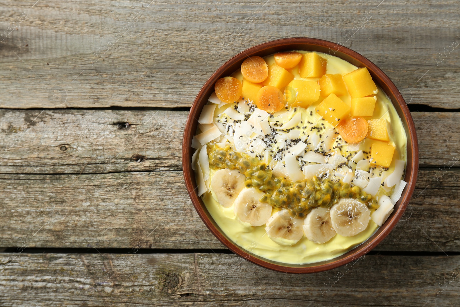 Photo of Tasty smoothie bowl with fresh fruits on wooden table, top view. Space for text