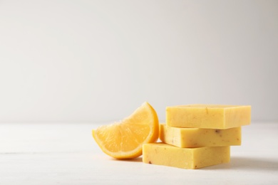 Photo of Handmade soap bars and citrus fruit on white table. Space for text