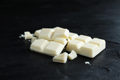 Pieces of delicious white chocolate on black table