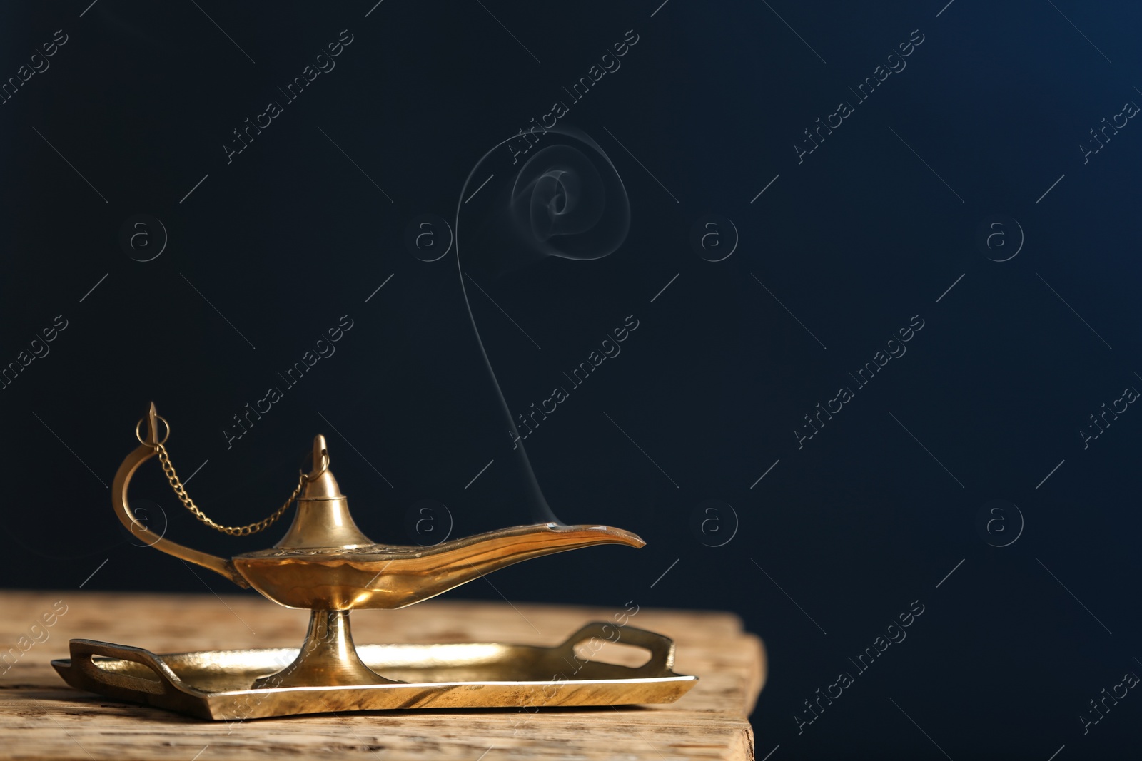 Photo of Aladdin lamp of wishes on wooden table against dark background