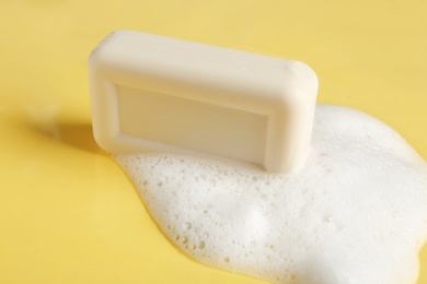 Soap bar and foam on color background