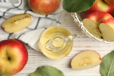 Photo of Natural apple vinegar and fresh fruits on white wooden table, flat lay