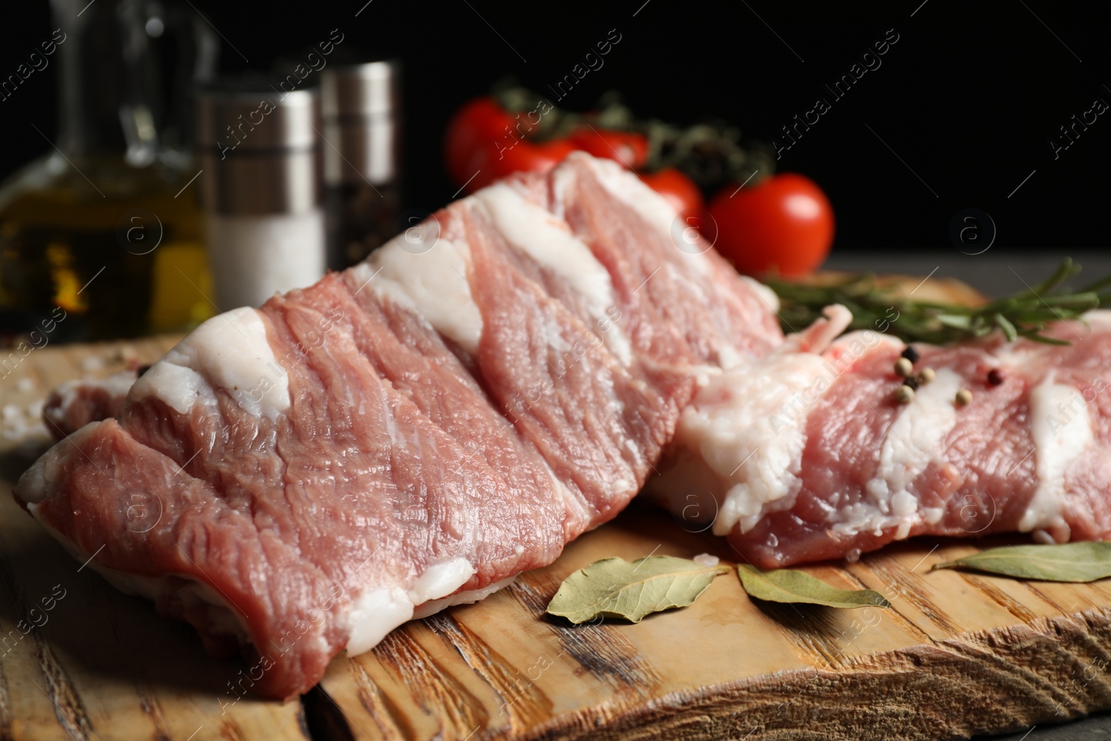 Photo of Raw ribs with bay leaves and pepper on wooden board, closeup