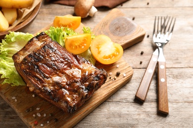 Delicious barbecued ribs served with garnish on wooden board