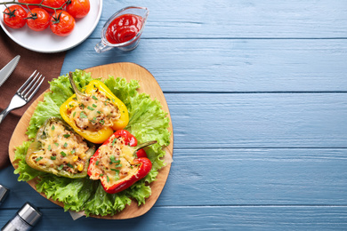 Photo of Tasty stuffed bell peppers served on blue wooden table, flat lay. Space for text