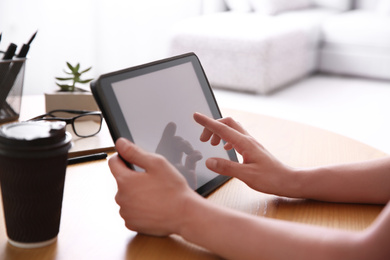 Photo of Woman working with modern tablet at wooden table, closeup