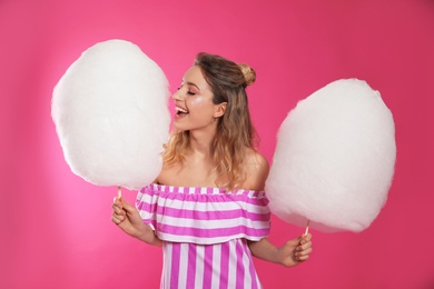 Portrait of pretty young woman with cotton candy on pink background