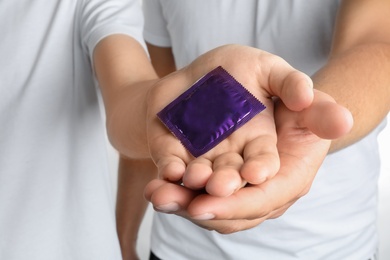 Photo of Young gay couple holding condom together, closeup