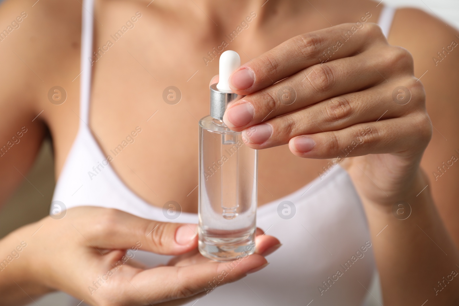 Photo of Woman with bottle of cosmetic serum, closeup