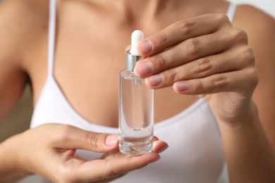 Photo of Woman with bottle of cosmetic serum, closeup