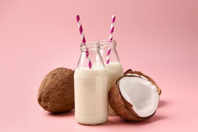 Photo of Delicious vegan milk and coconuts on pink background