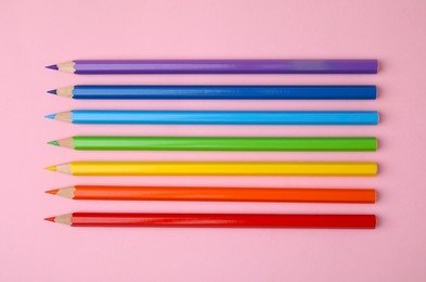 Colorful wooden pencils on pink background, flat lay