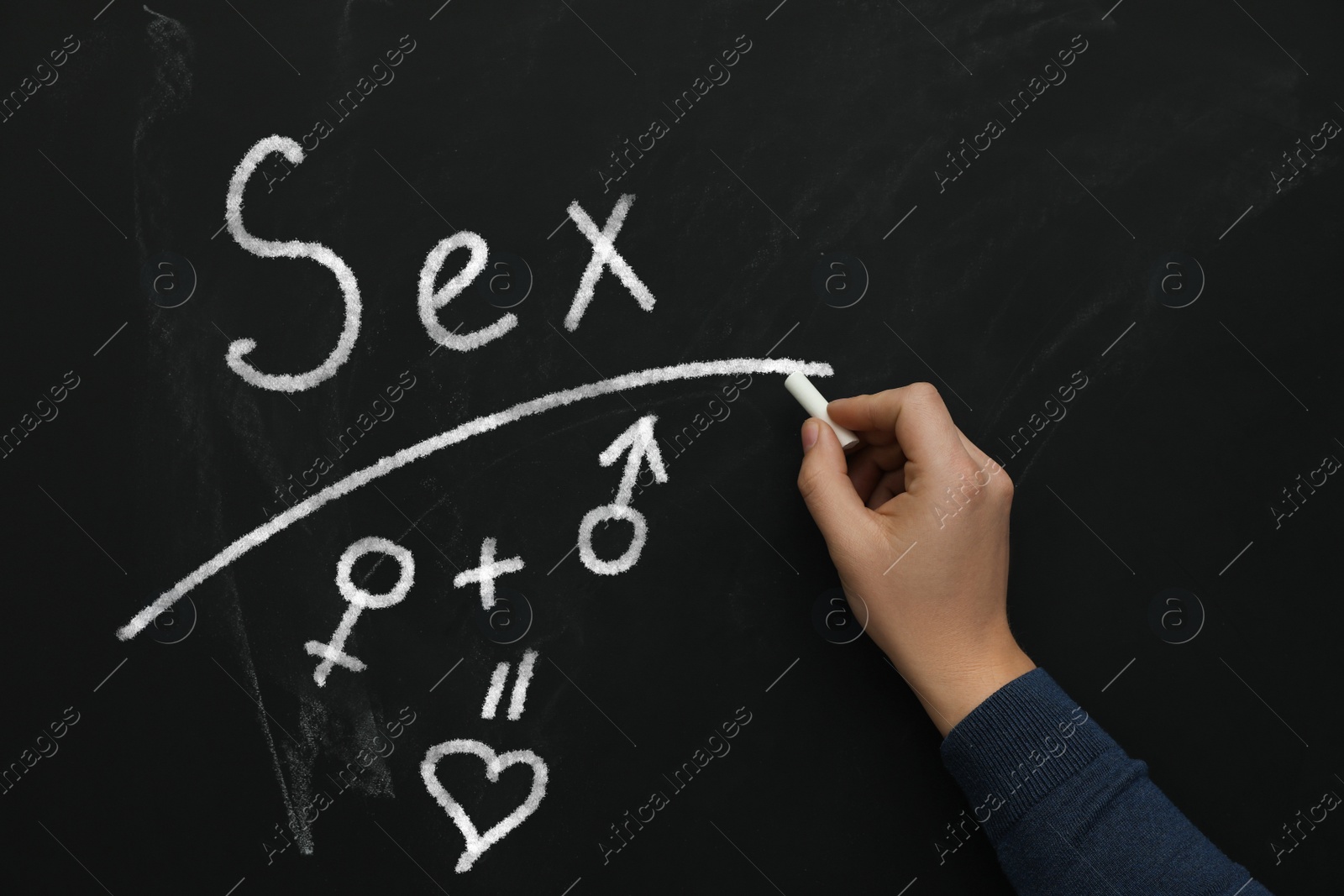 Image of Sexual education. Man underlining word Sex on black chalkboard, closeup. Chalked heart, female and male gender signs